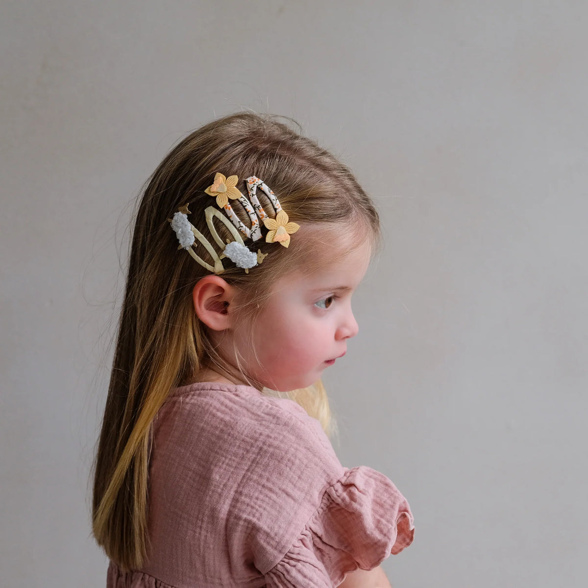 Young girl with decorative hair clip on a plain background