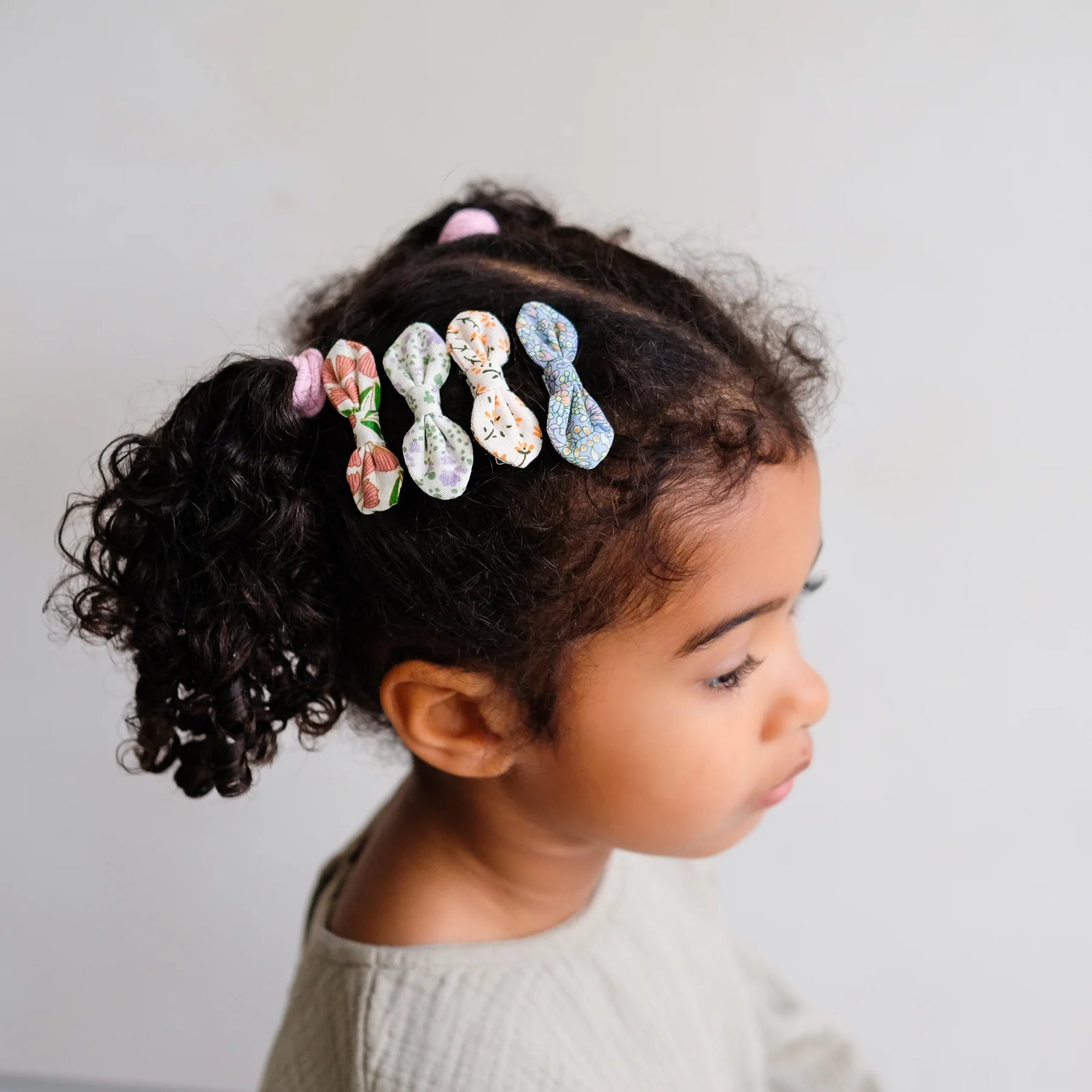 Child with floral hair clips in their hair against a plain background