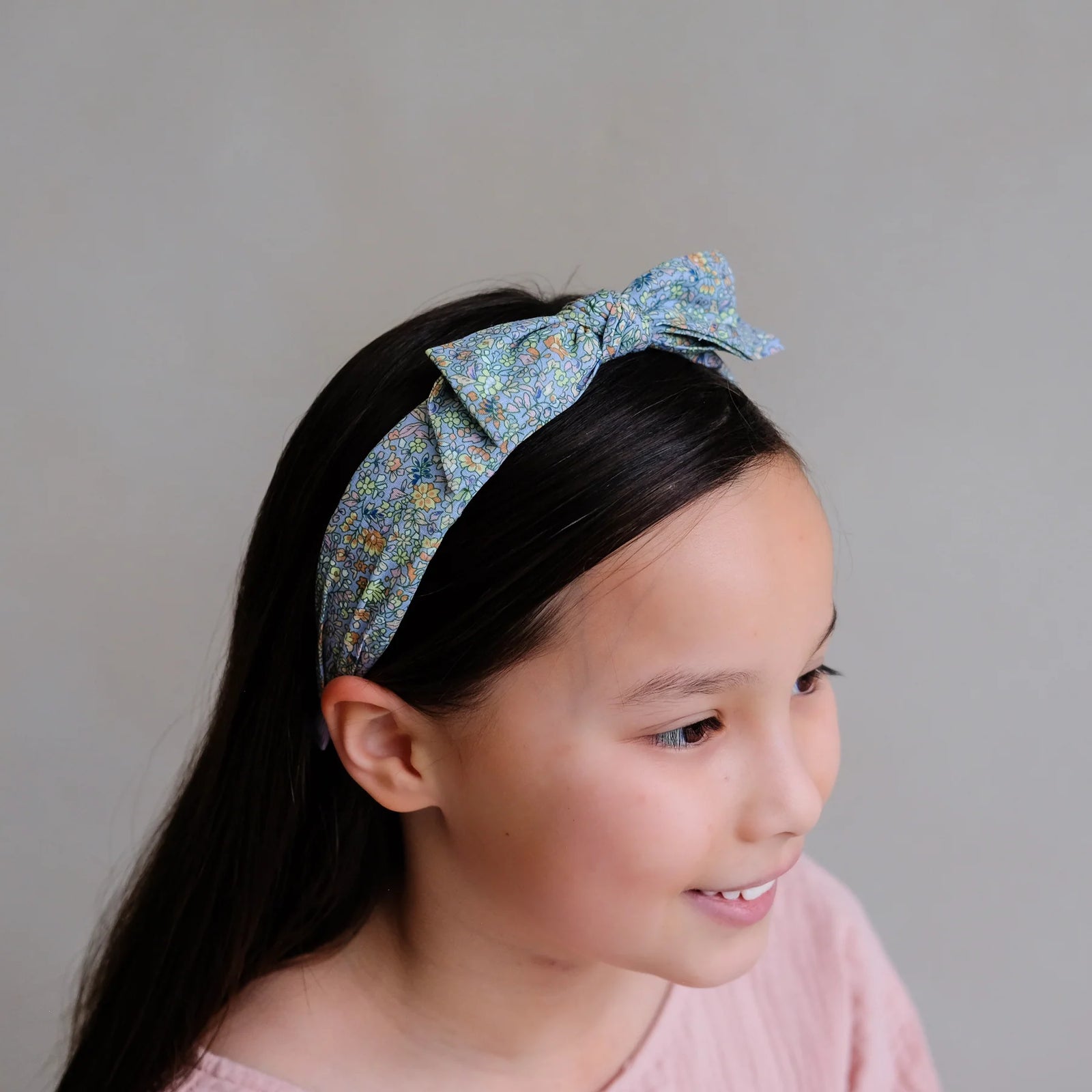 Young girl wearing a floral headband against a plain background