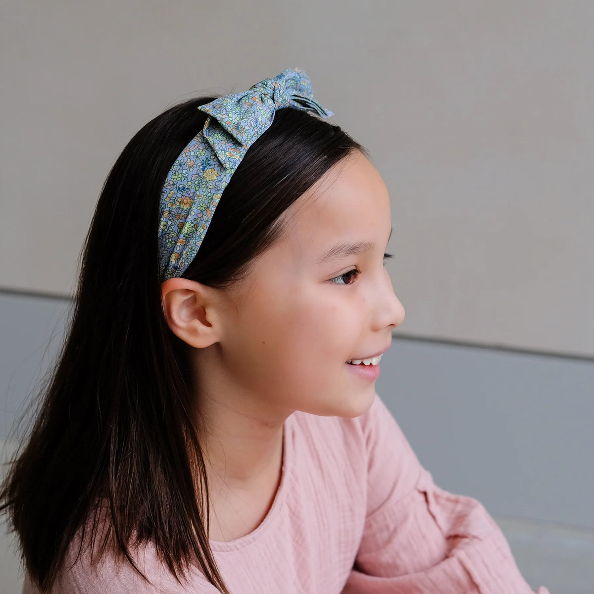 Young girl wearing a floral headband with a plain background