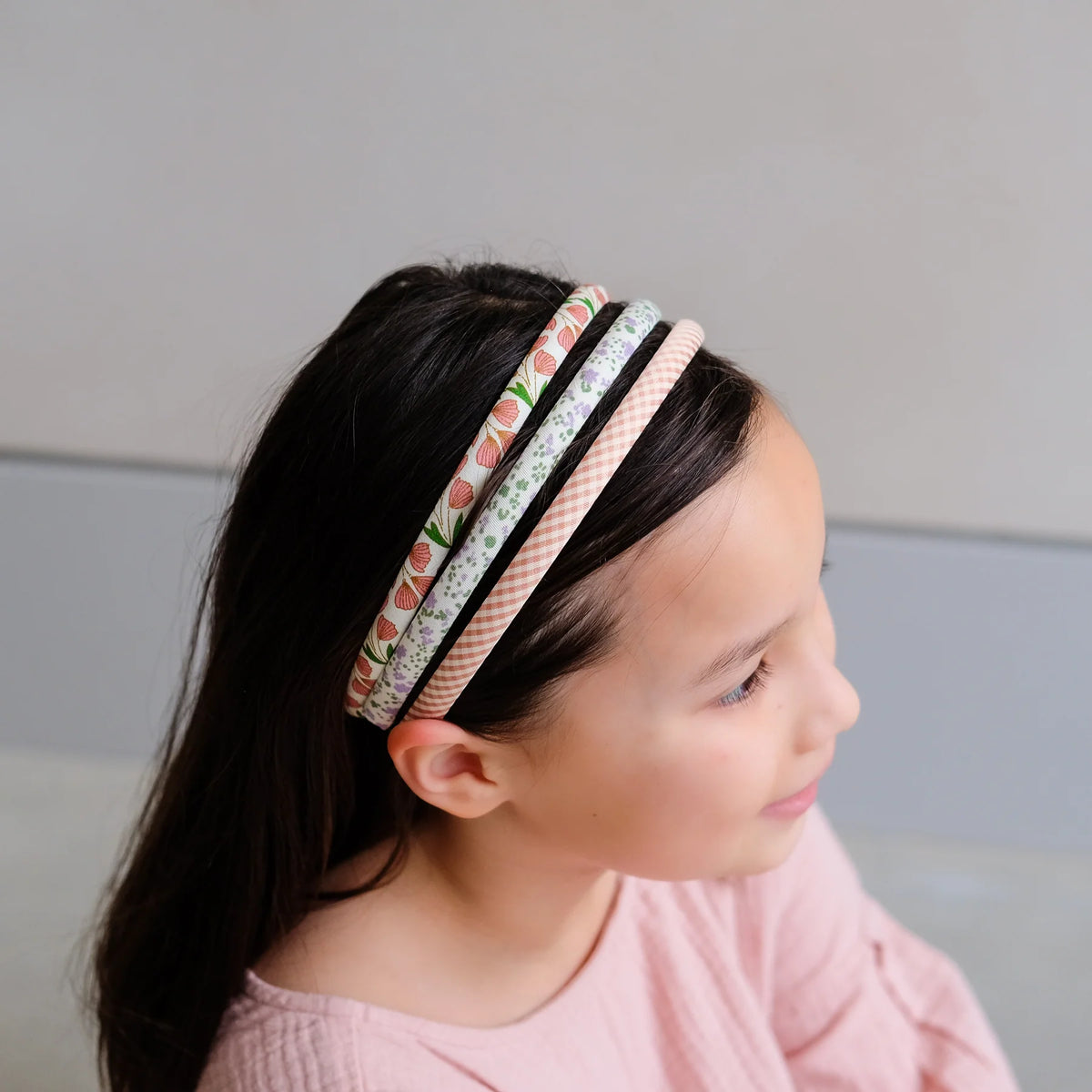Young girl wearing a colorful headband with a neutral background