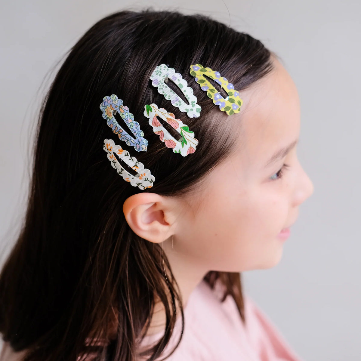 Girl with colorful hair clips in her hair against a neutral background