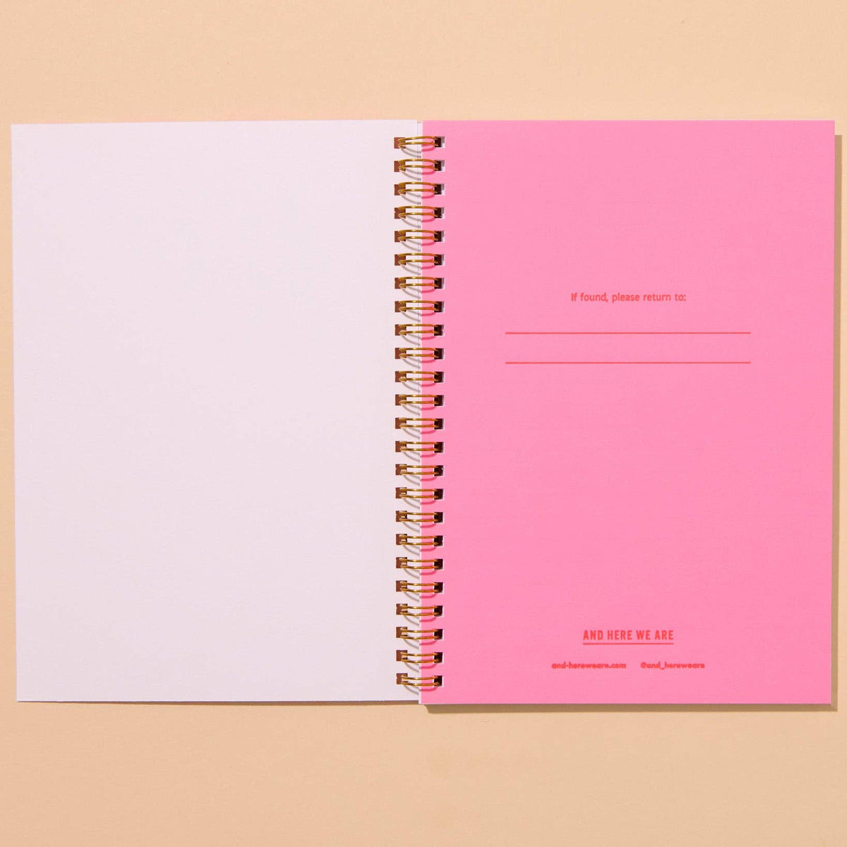 Pink spiral-bound notebook with white pages on a beige background
