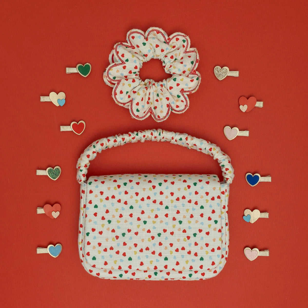 Small handbag and hair accessories with heart pattern on a red background