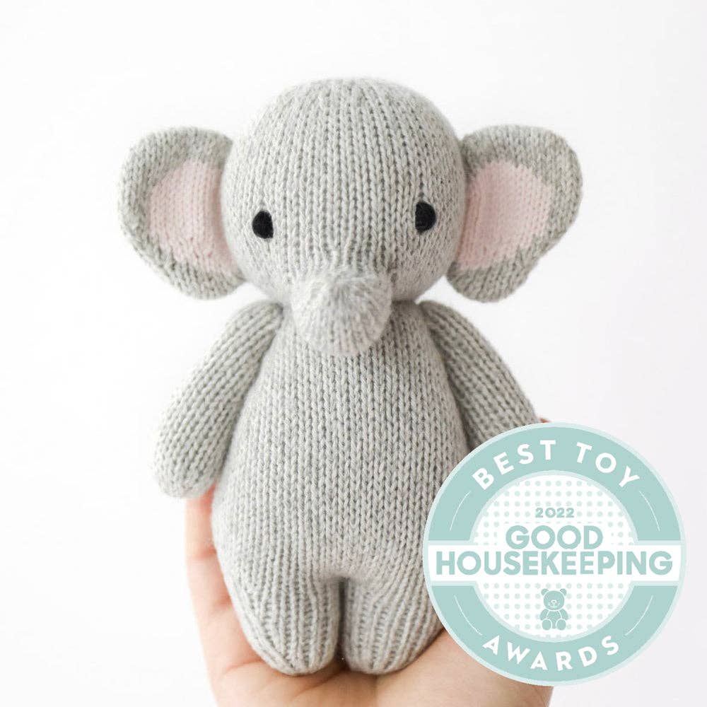 Knitted elephant toy held by a hand with Good Housekeeping Award badge