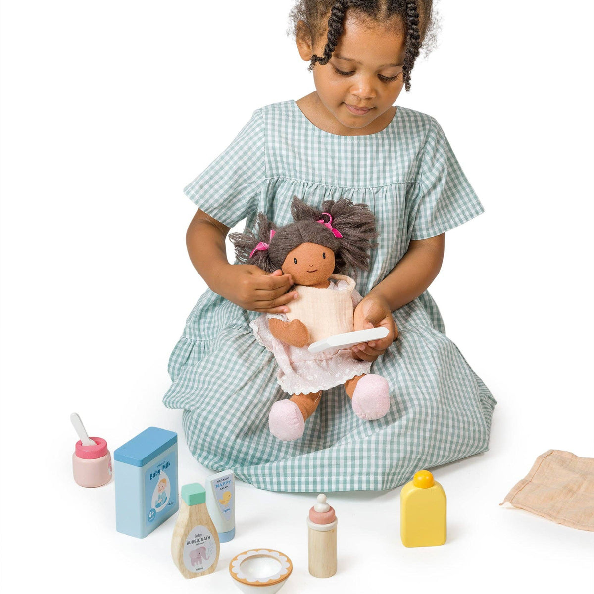 Young girl playing with a doll and toys on a white background