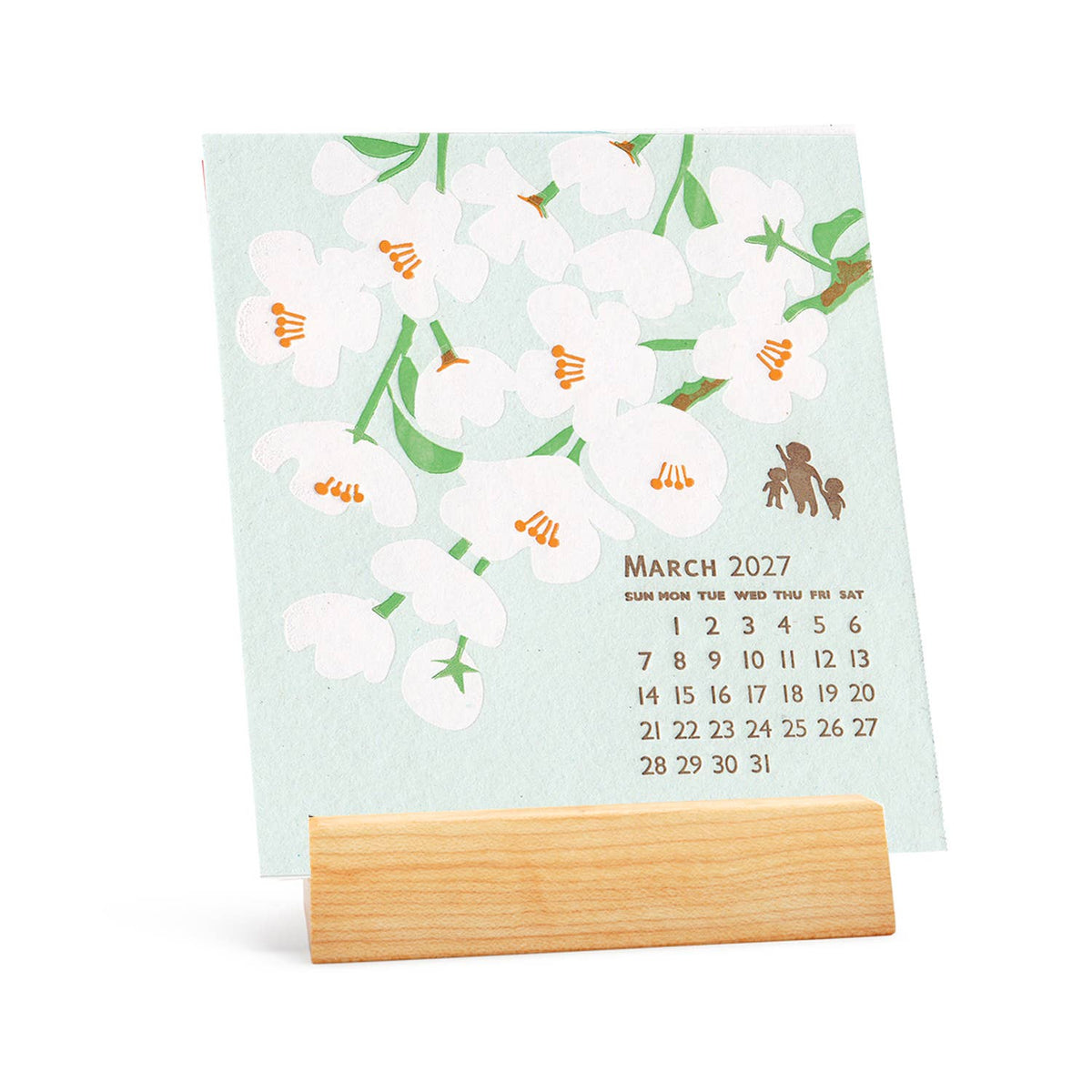 A square desk calendar card with a pale mint background, white cherry blossoms, green stems, and a small bee illustration, displayed on a light wood stand against a white background.