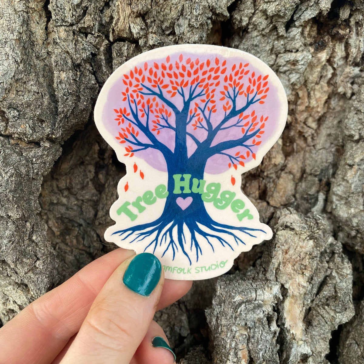 Sticker with tree design and &#39;Tree Hugger&#39; text held against a tree trunk.