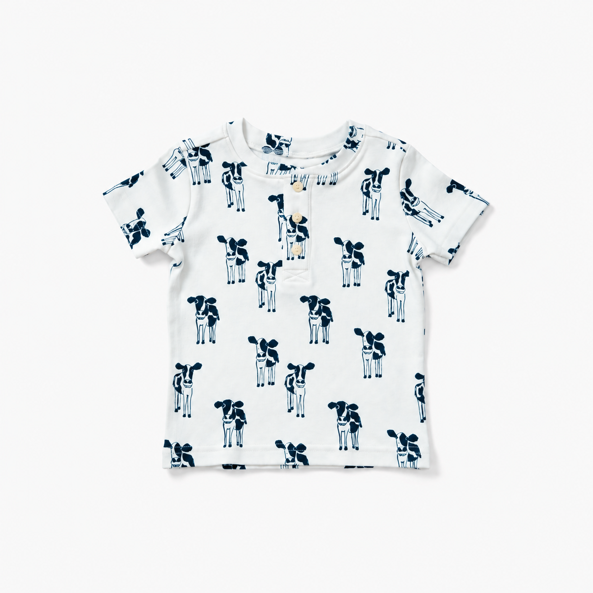 A white short-sleeve baby t-shirt with an all-over navy blue cow print, laid flat against a clean white background.