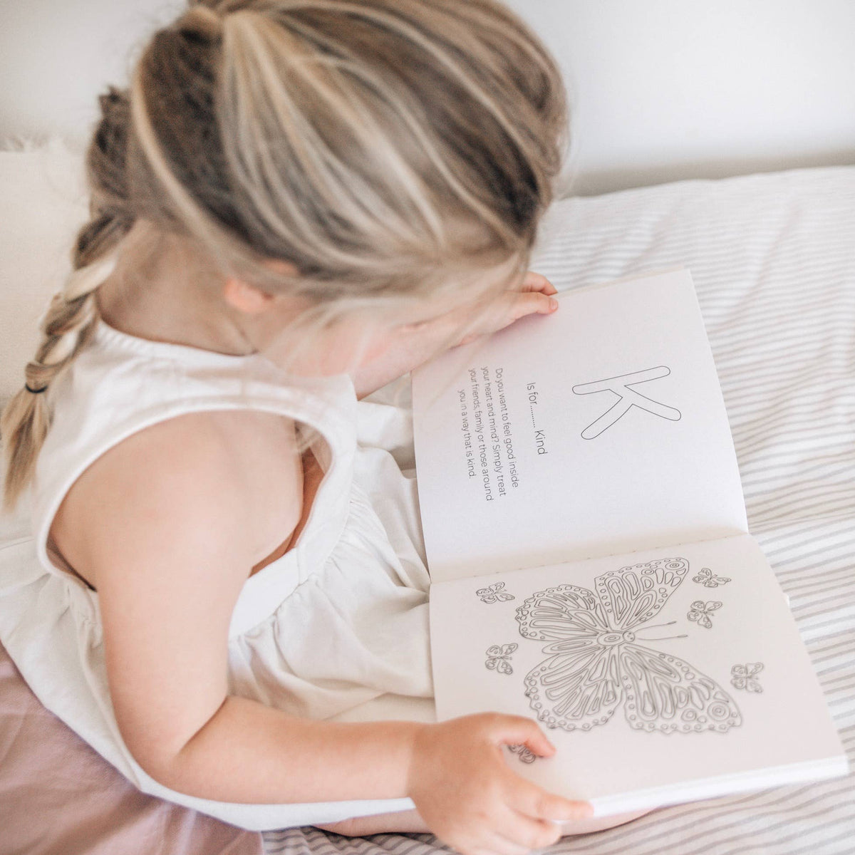 Child reading a book with butterfly illustrations on a soft surface