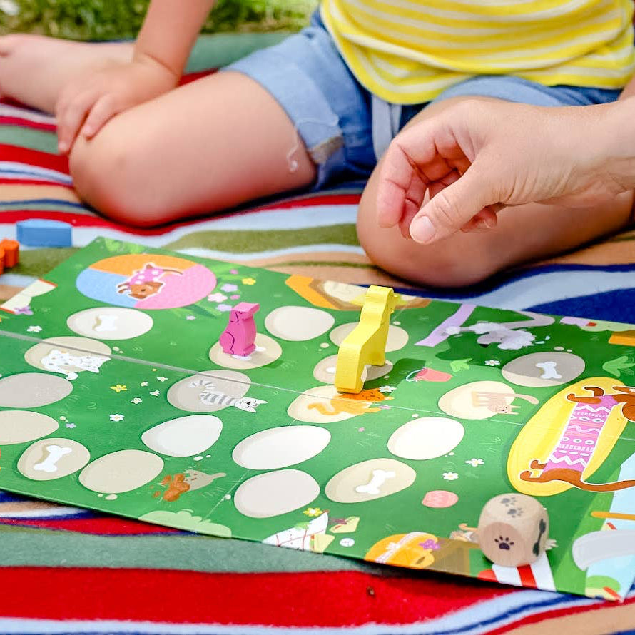 Children playing with a board game on a colorful blanket outdoors
