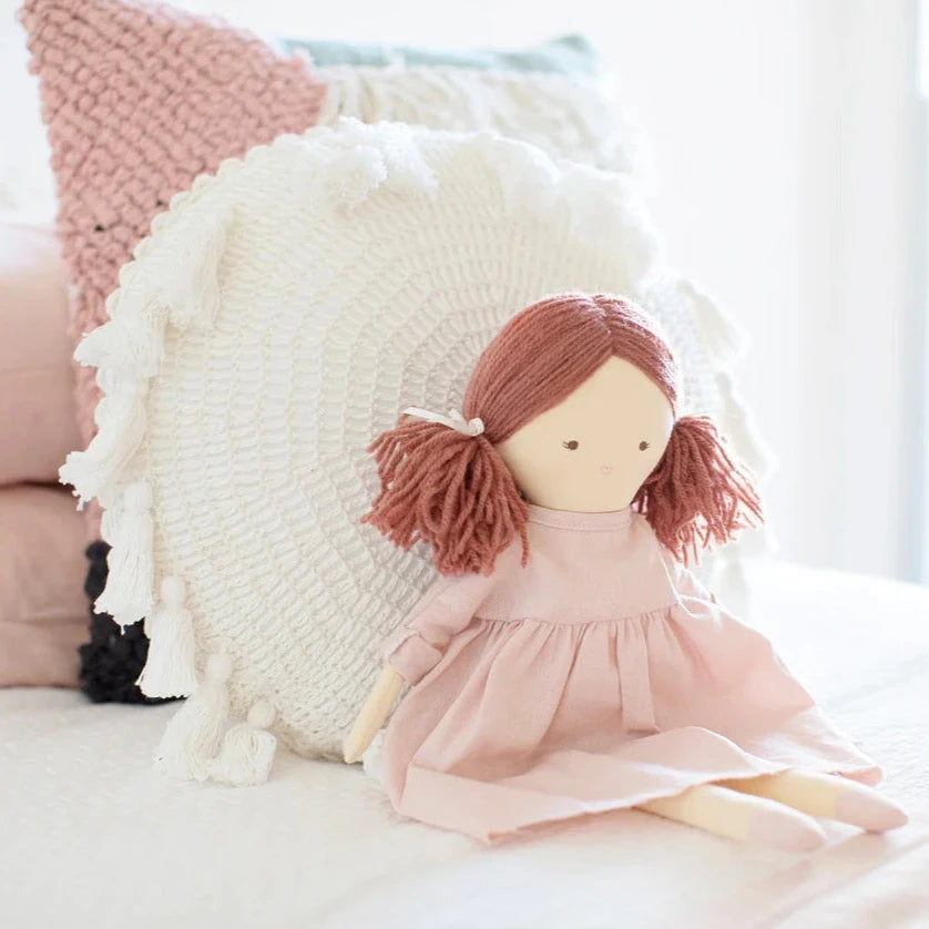 child holding doll with long red ponytails and pink dress
