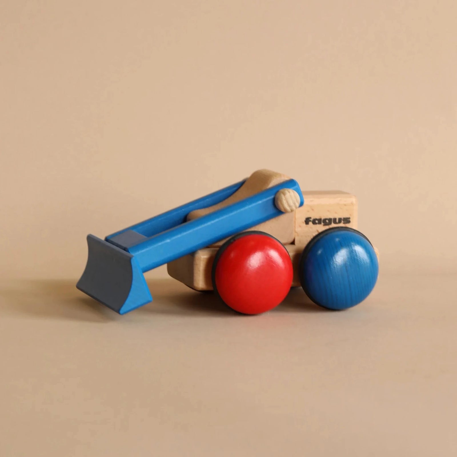 Wooden bulldozer toy with blue and red wheels on a beige background