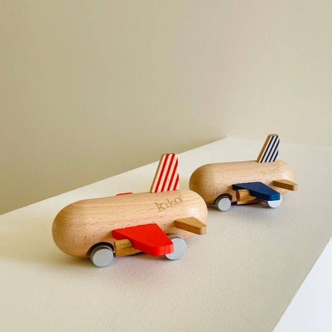 Two wooden toy cars with striped flags on a beige surface