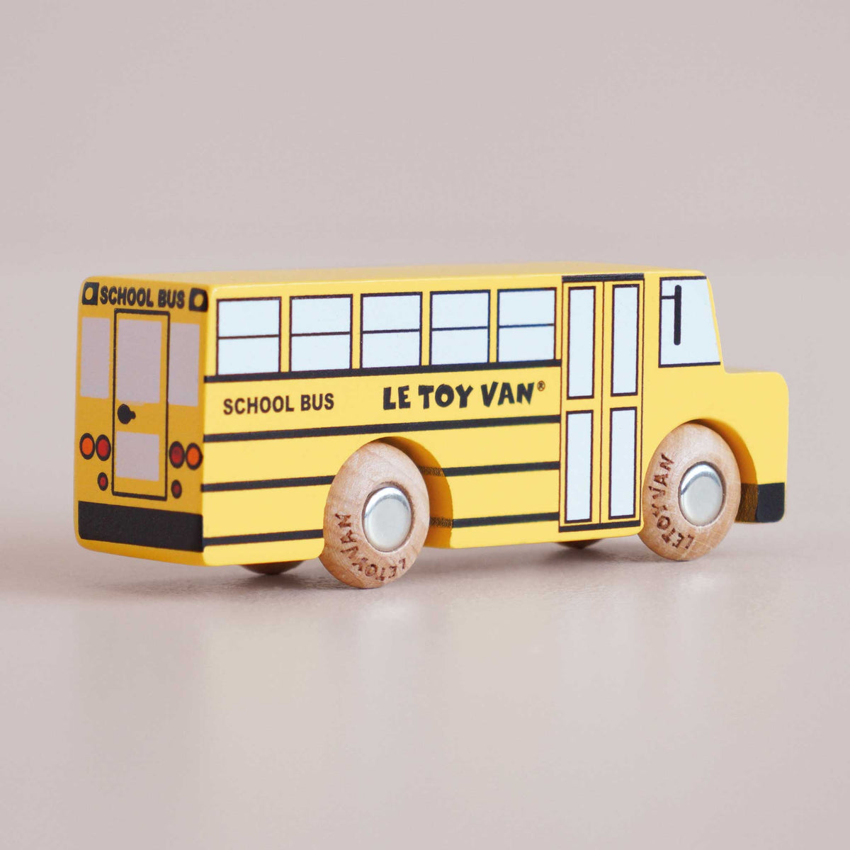 Yellow toy school bus with wooden wheels on a beige background, branded 'Le Toy Van'.