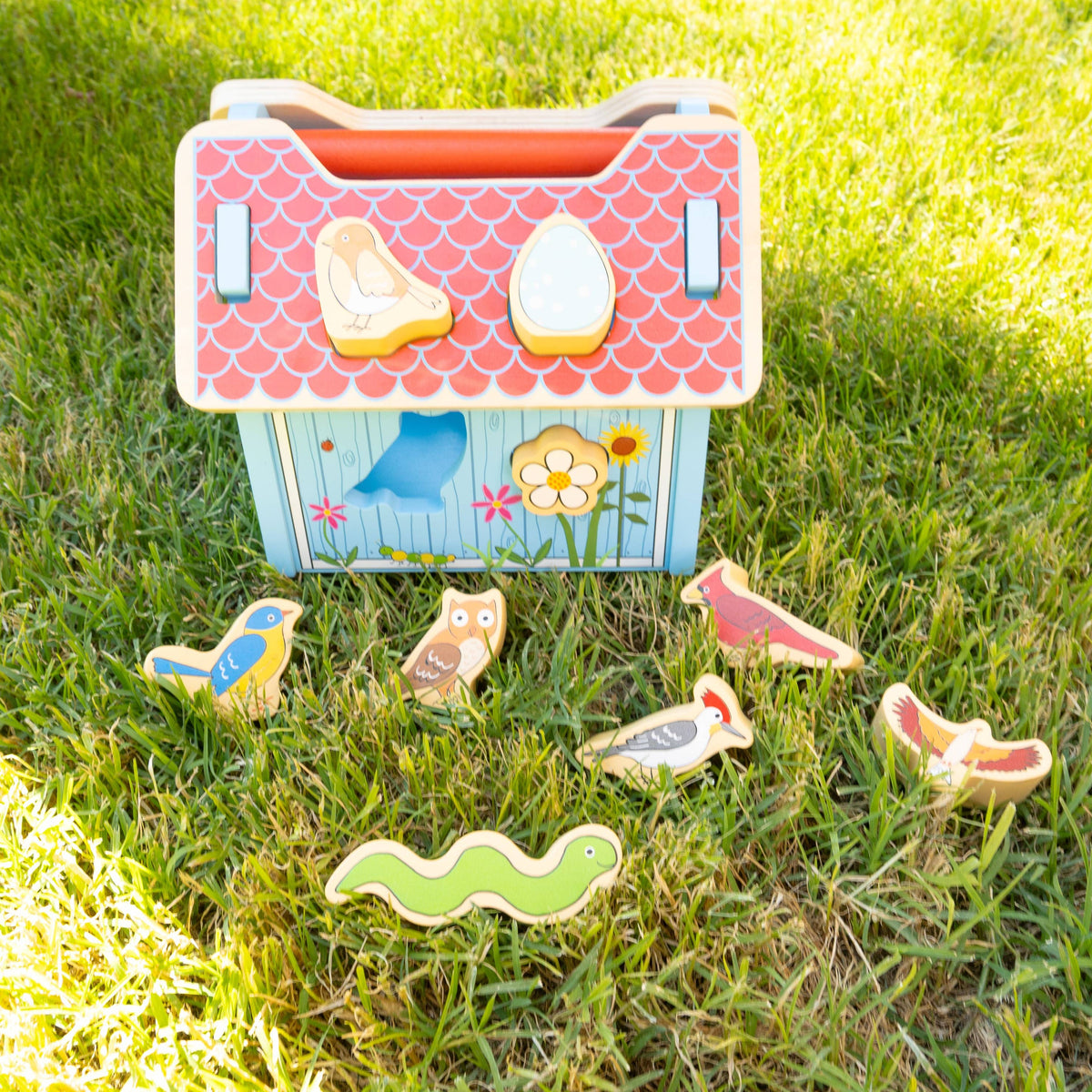 Children's toy house with animal figures on a grassy background