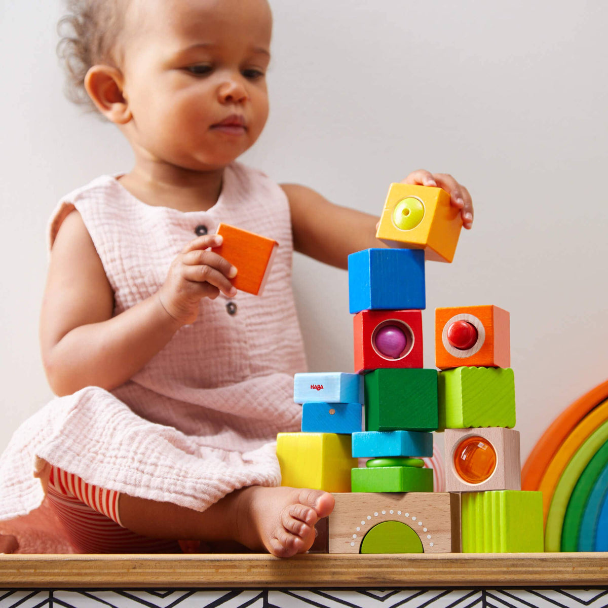 Child playing with colorful wooden blocks on a white background
