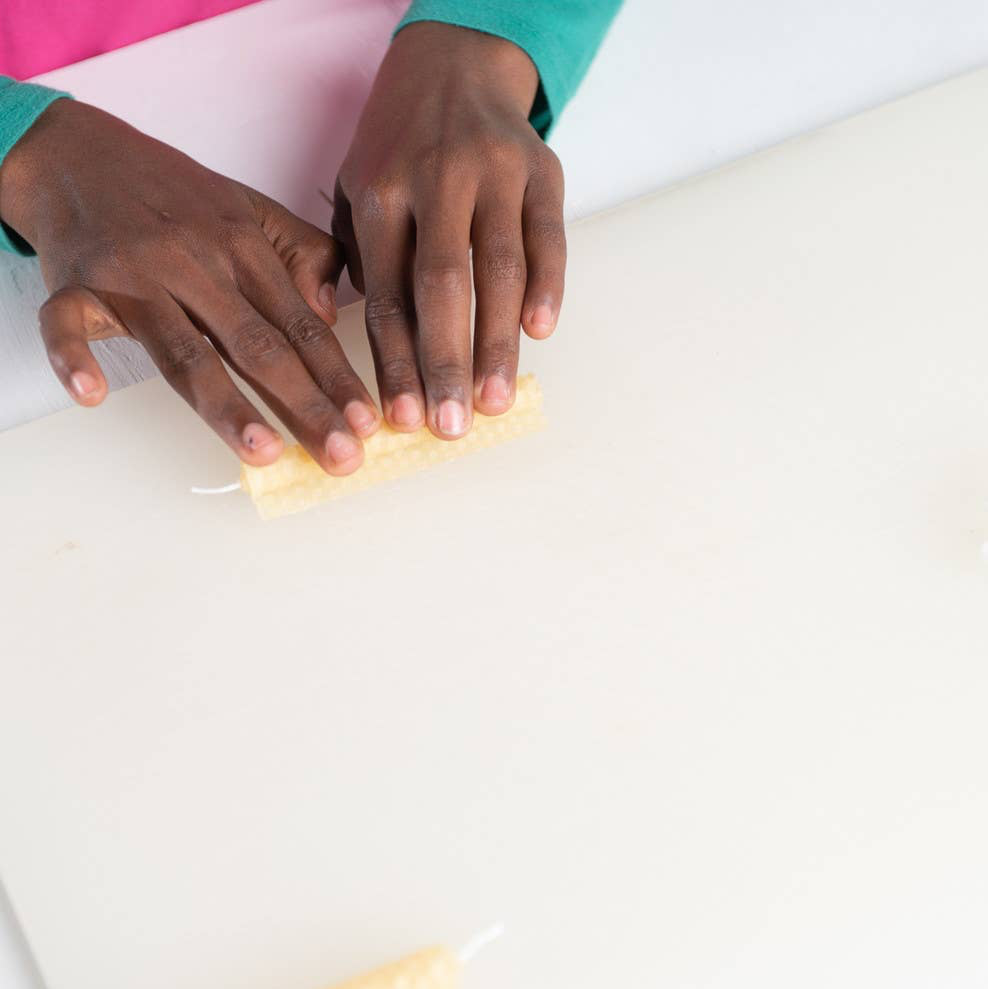 Close-up of hands using a yellow sponge on a white surface