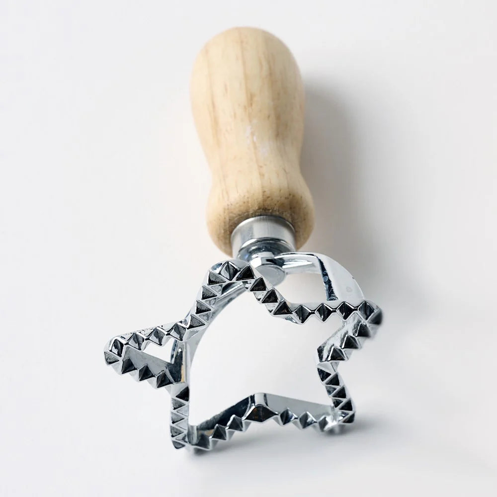 Metal star-shaped cookie cutter with wooden handle on a light background
