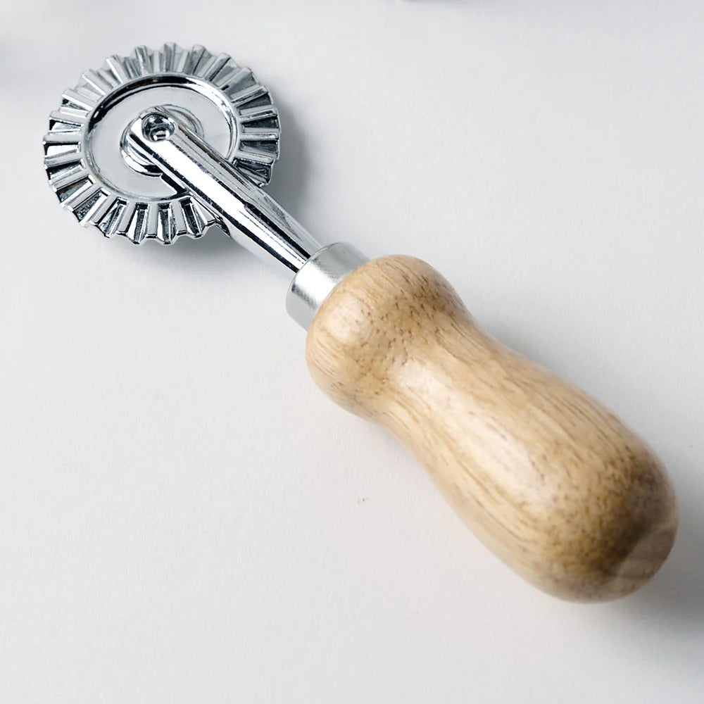 Metal dough roller with wooden handle on a light gray background