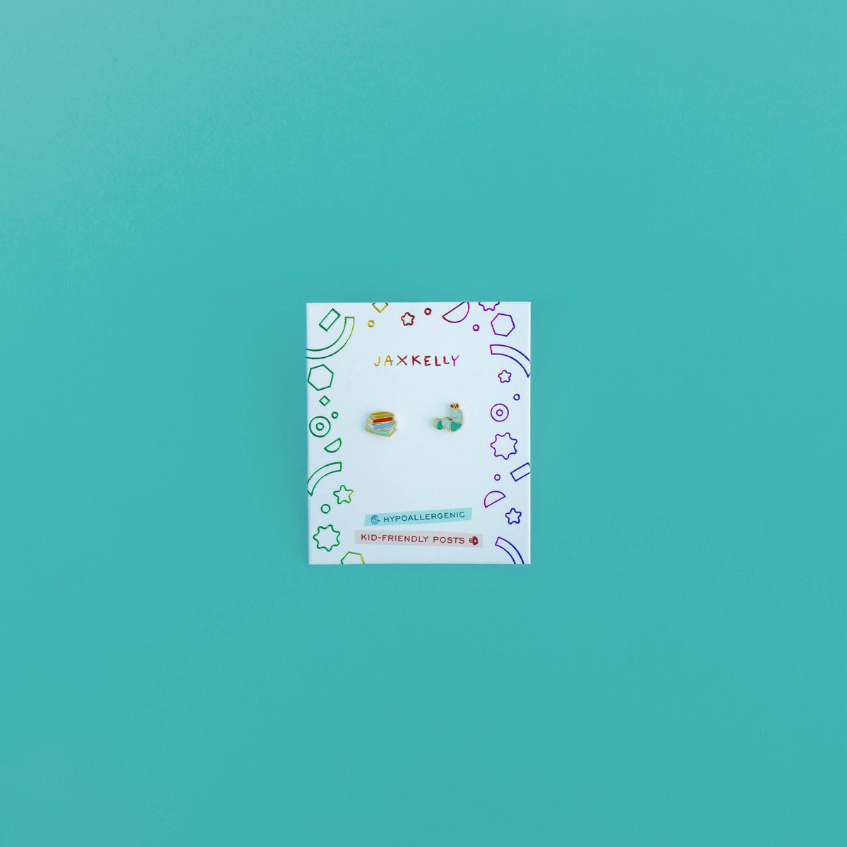 Set of earrings on a card with decorative patterns against a teal background
