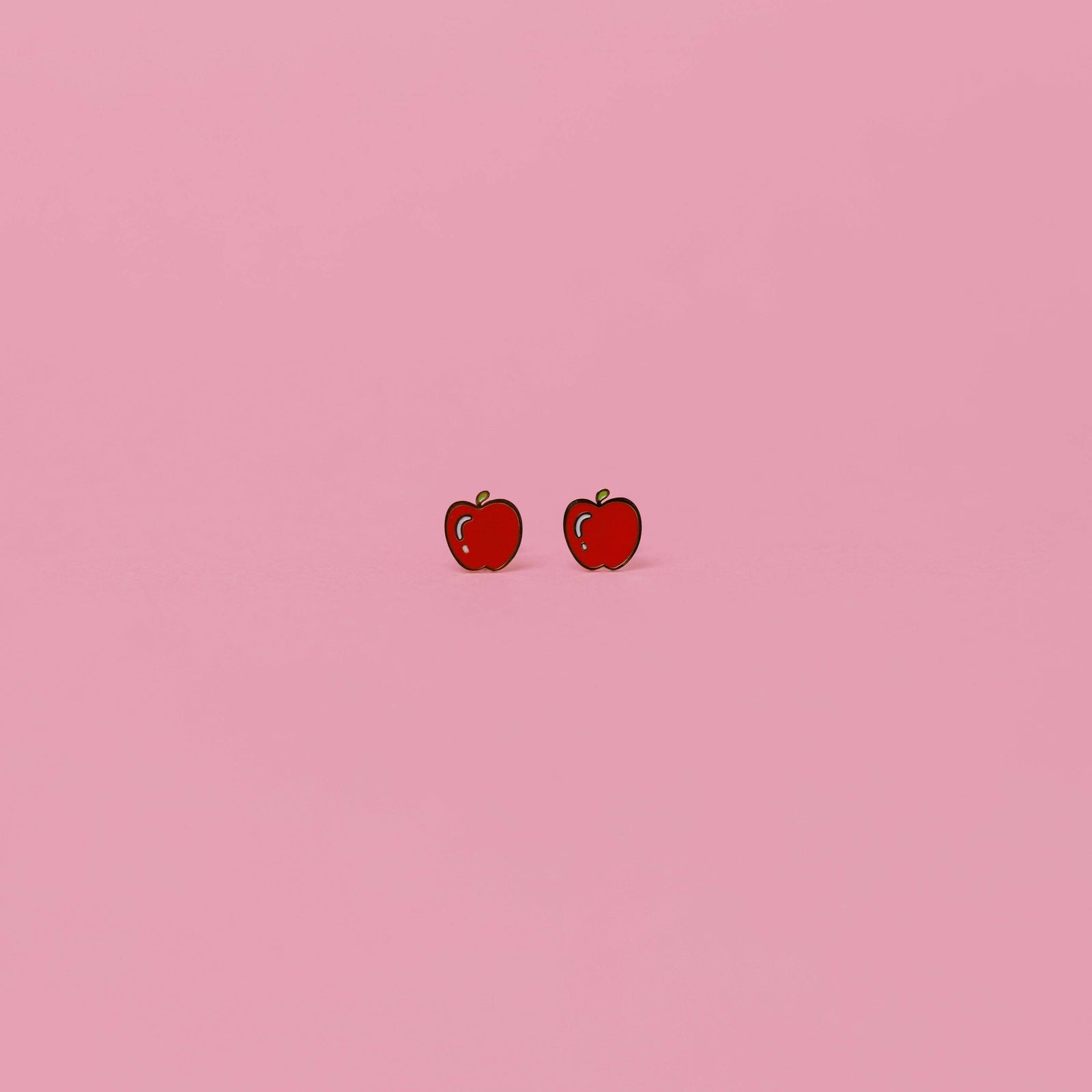 Card with apple-shaped earrings on a pink background