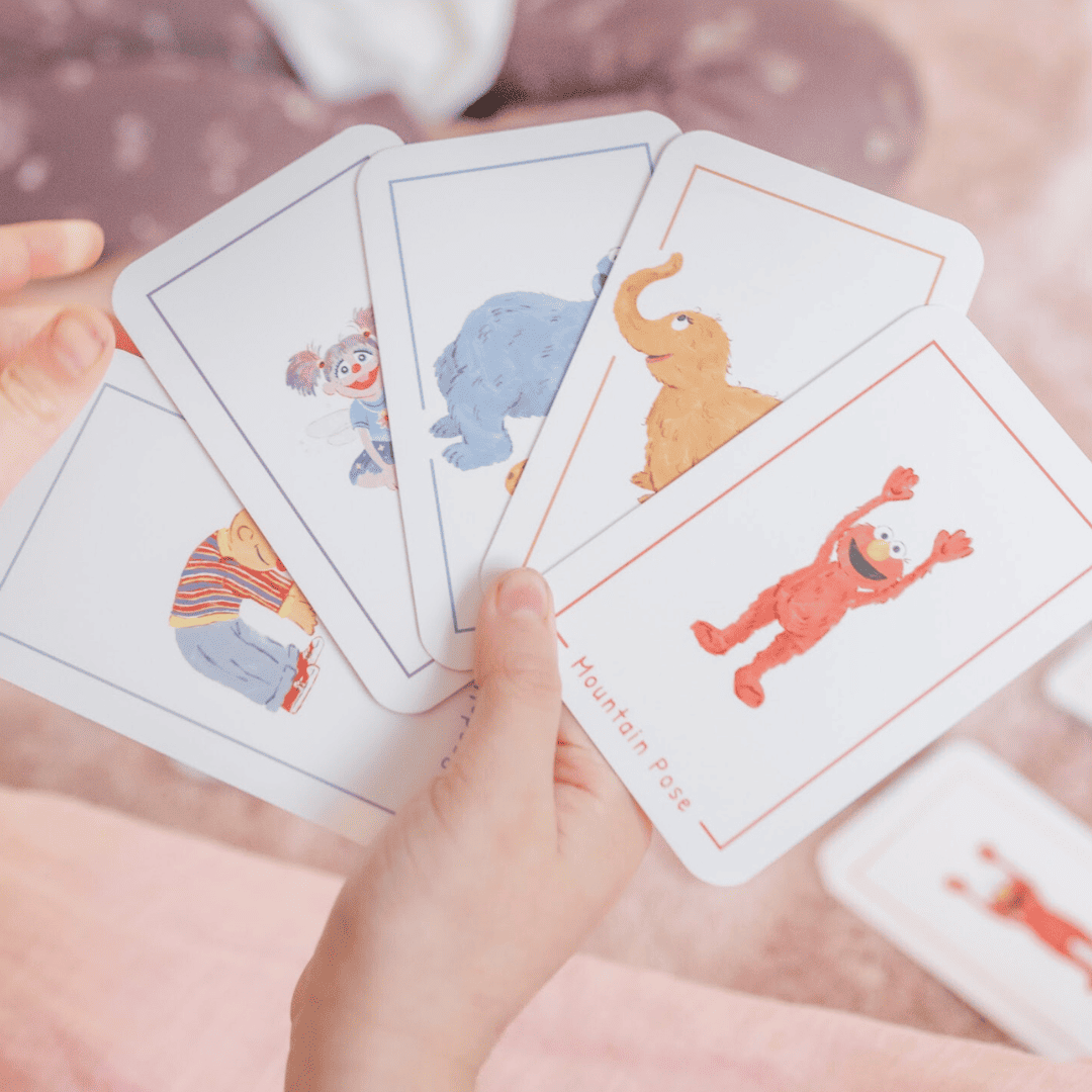 Children's educational cards with animal illustrations held by a child's hand.