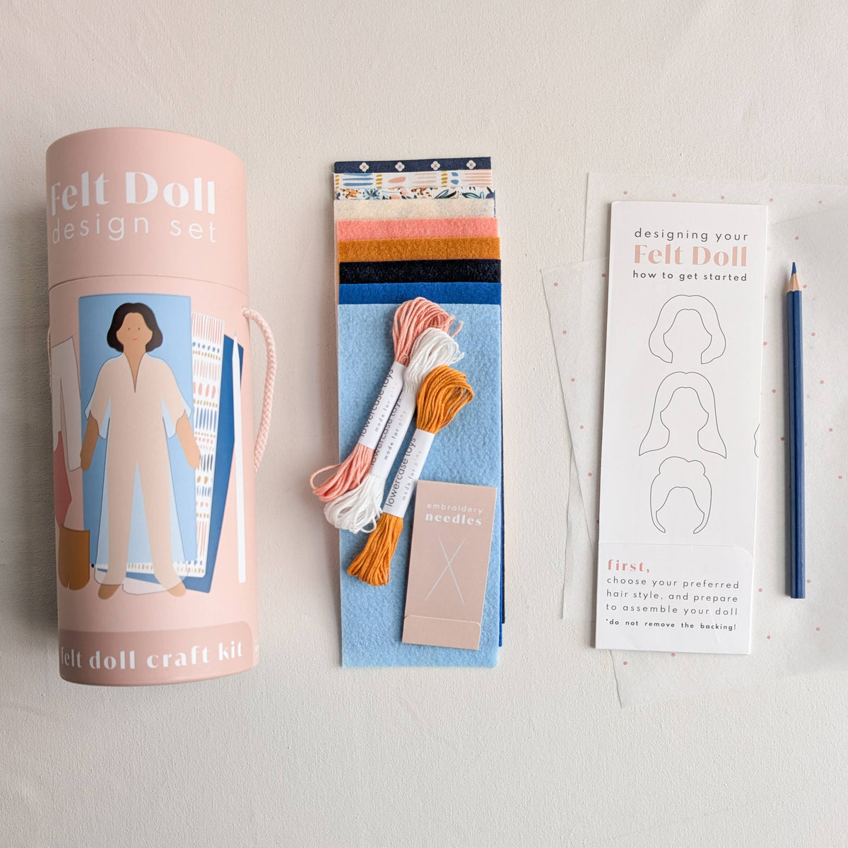 Felt doll design set with cylindrical packaging, colorful materials, and instructions on a light gray background.