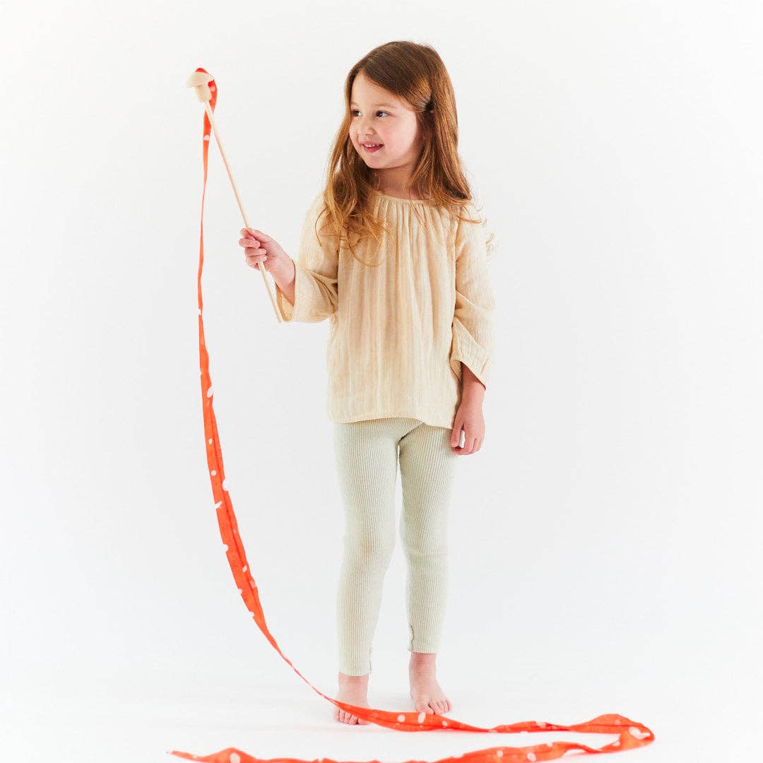 Young girl holding a long red ribbon on a white background