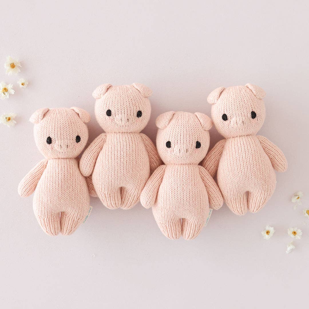 Four pink knitted pigs on a light background with small flowers.