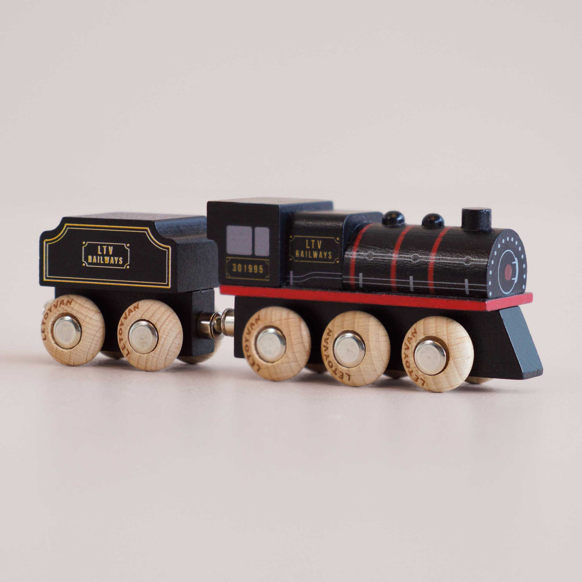 Wooden toy train with black engine and red trim on a light gray background