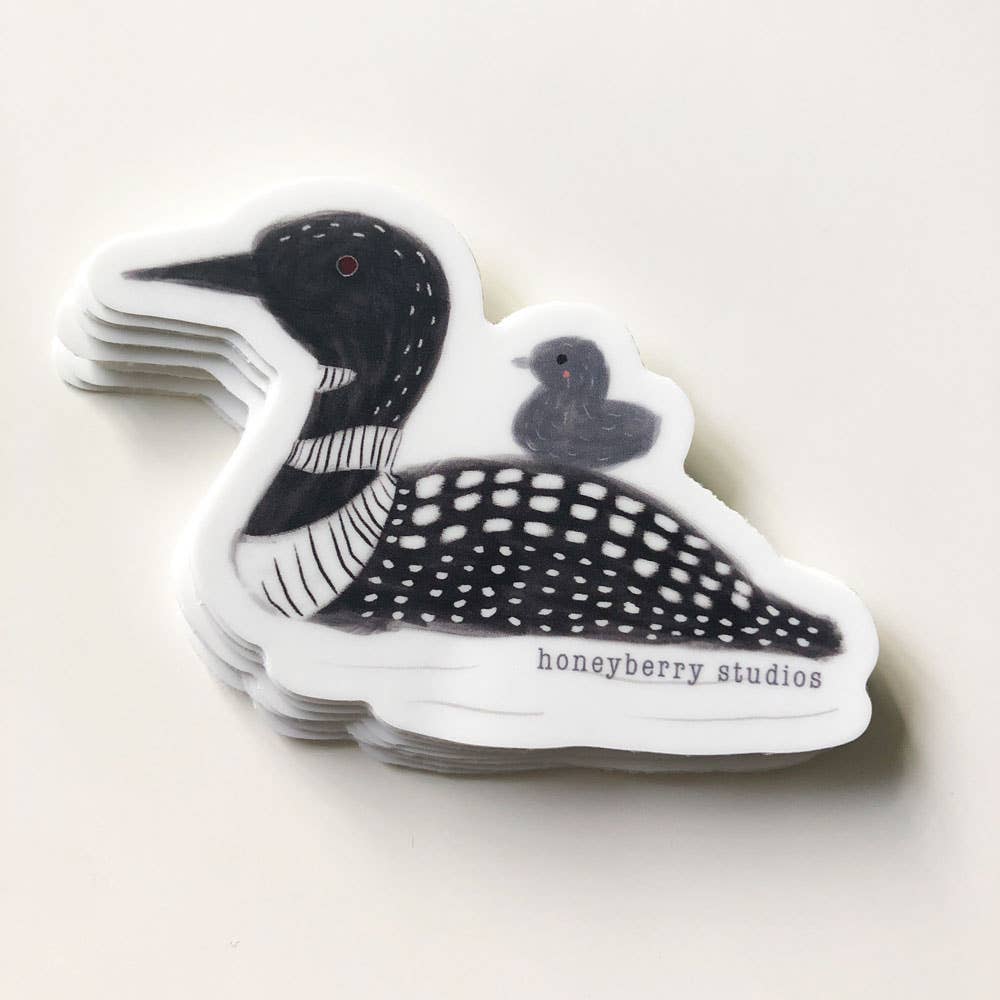 Stack of loon bird stickers with 'honeyberry studios' branding on a light background