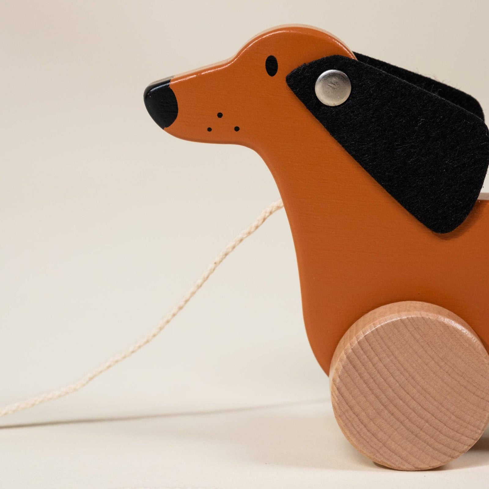 Wooden dachshund pull toy on a beige background