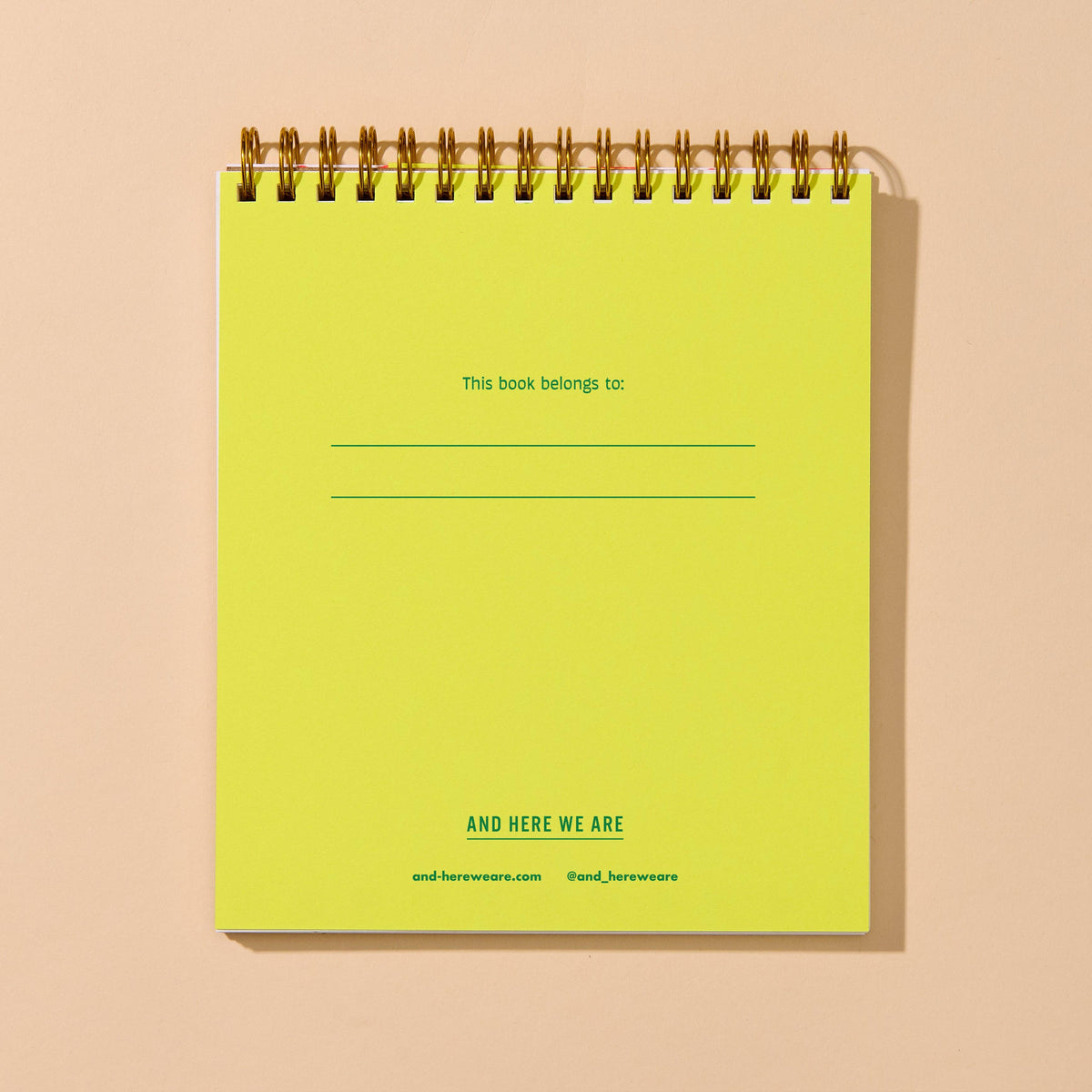 A lime green spiral-bound notebook with gold metal coils, featuring placeholder text on the cover, set against a solid beige background.