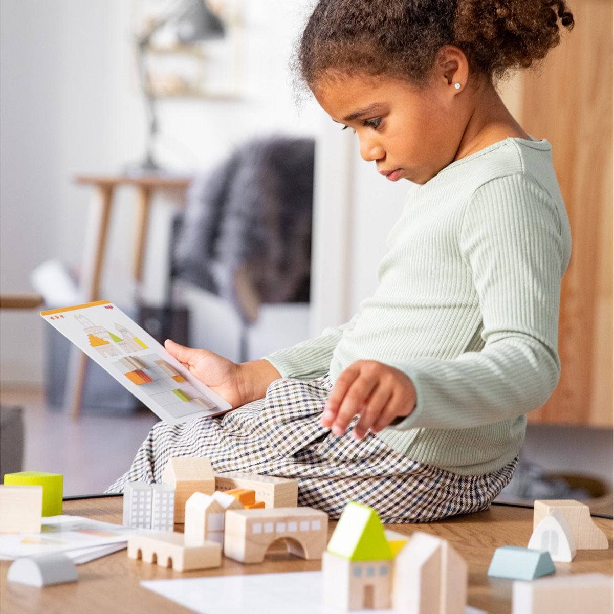 Child playing with wooden blocks and a tablet in a home setting