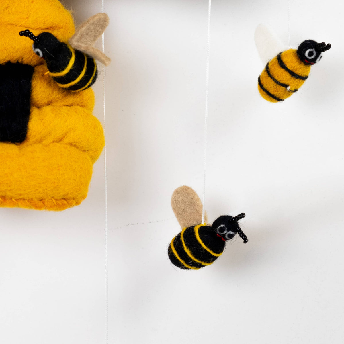 Three bee-shaped toys hanging against a white background