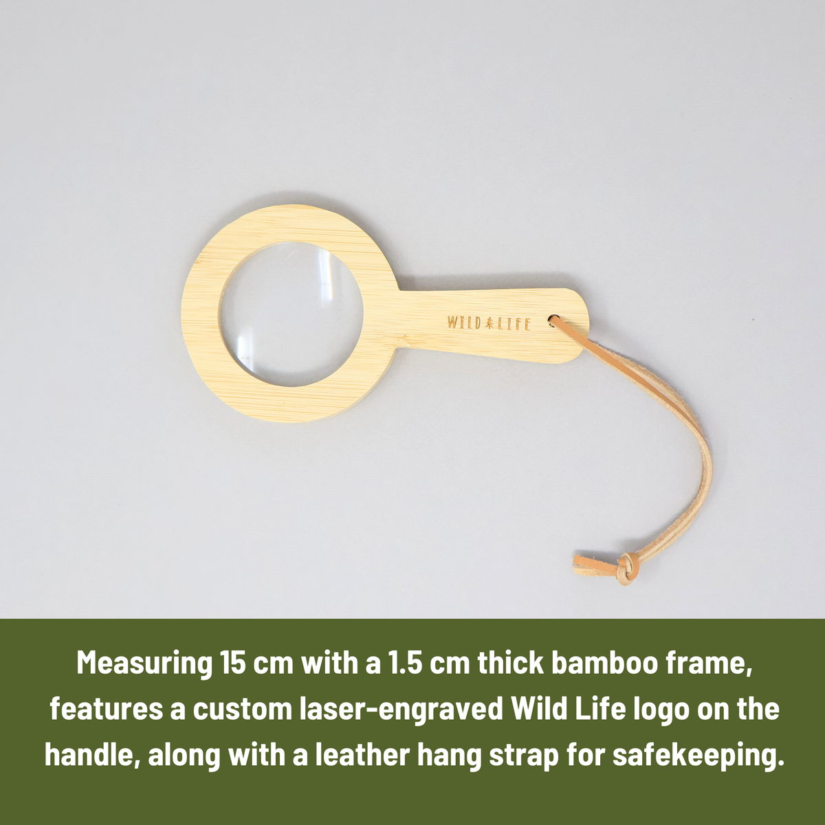Wooden magnifying glass with a leather strap on a gray background