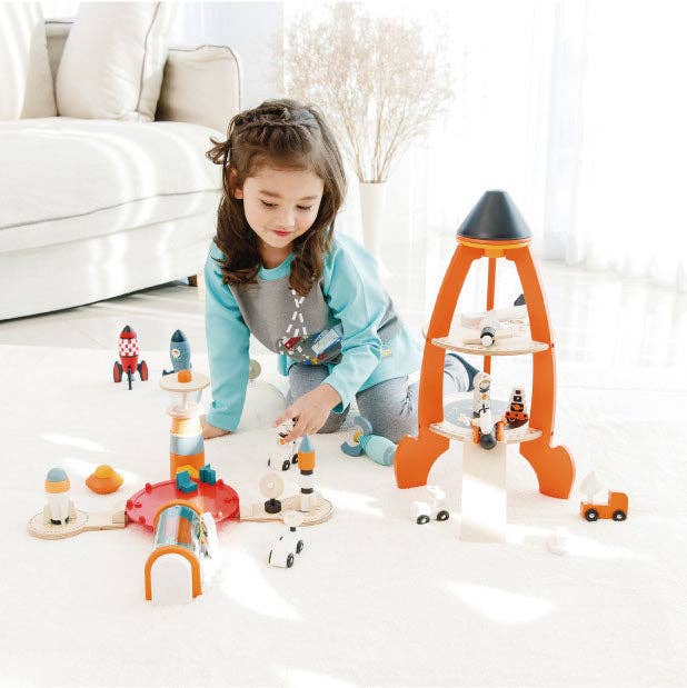 Child playing with toy rocket launchers and space-themed figurines on a light-colored floor.