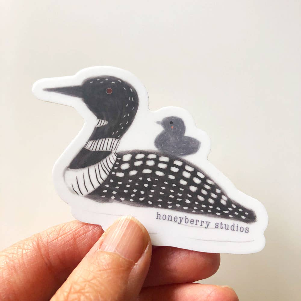 Sticker of a bird design held by a hand with 'honeyberry studios' branding.