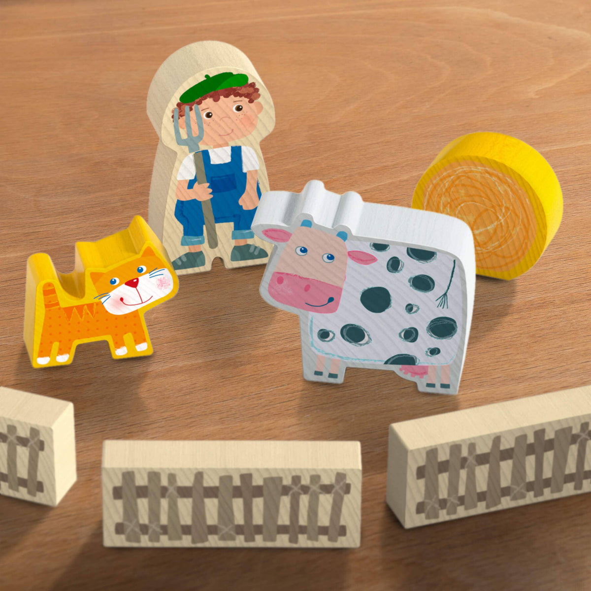 Wooden farm toy set with farmer, animals, and blocks on a wooden surface