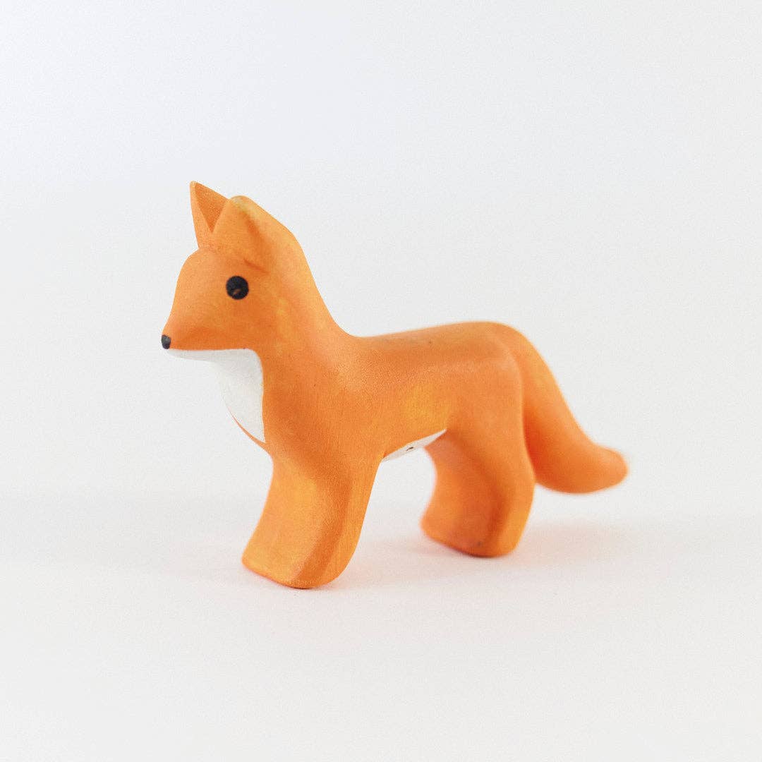 A small orange fox figurine with a white chest and black eyes, standing on a plain white background.