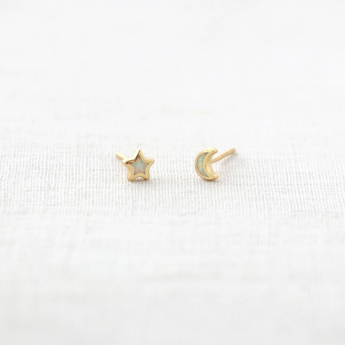Gold star and moon earrings on a white background