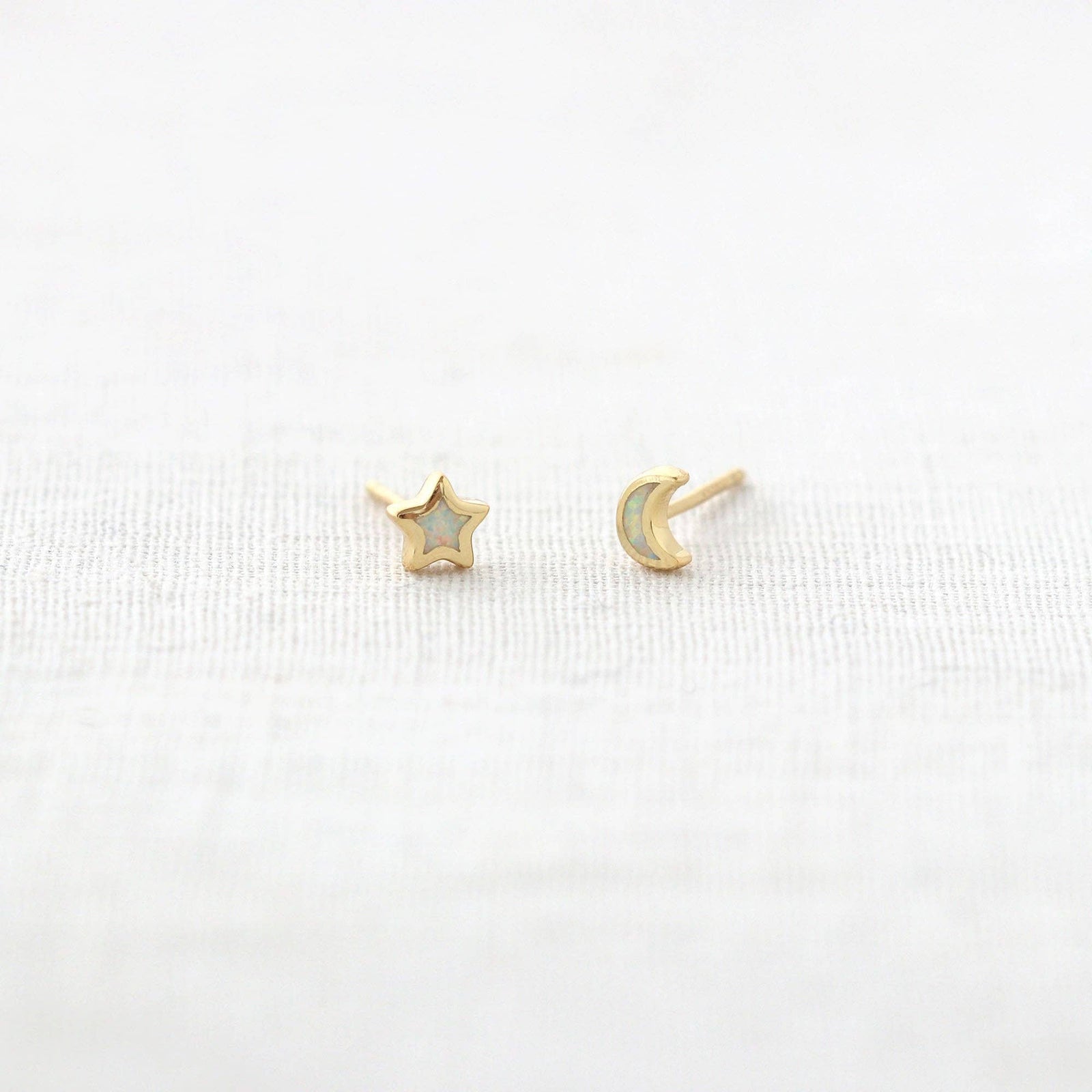 Gold star and moon earrings on a white background