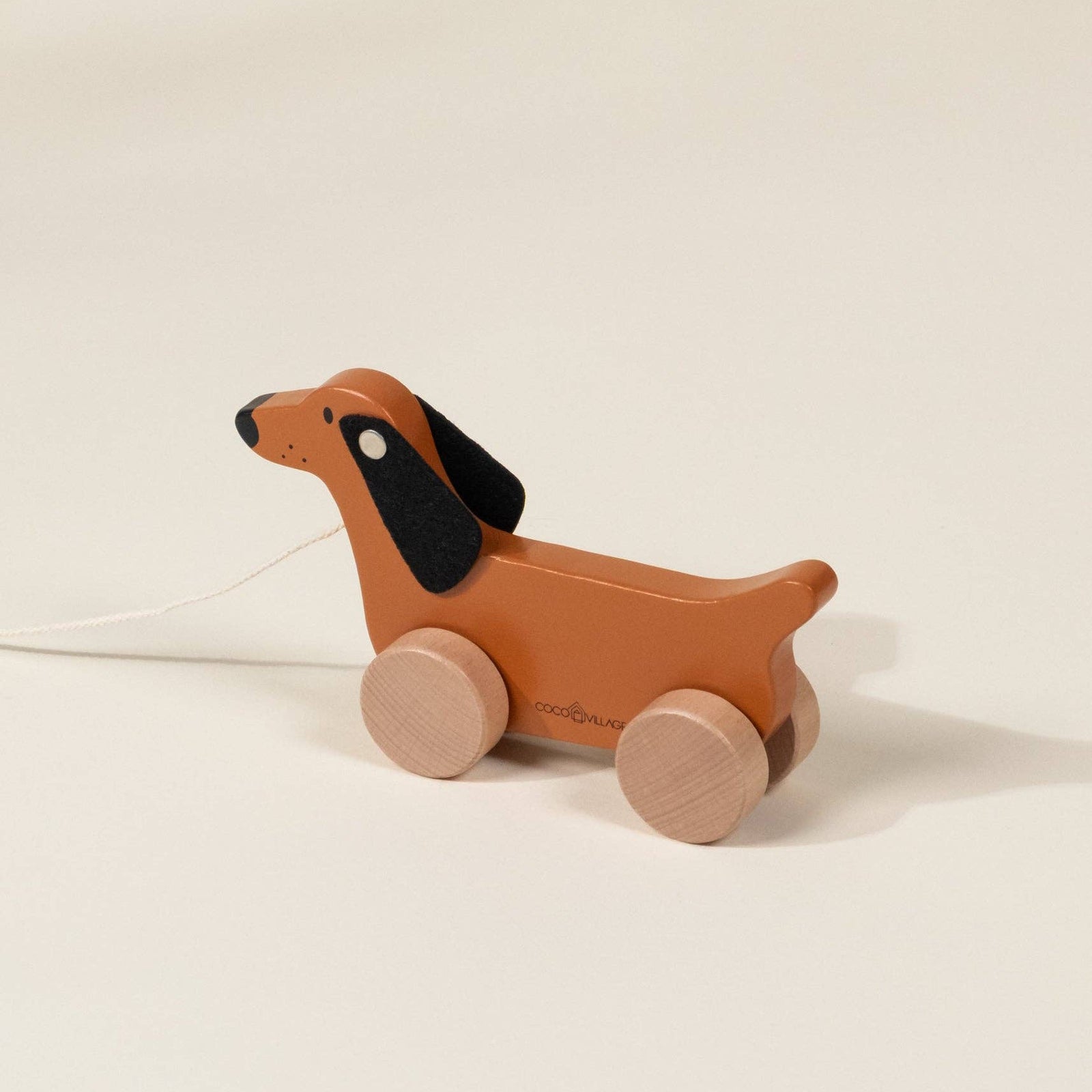 Wooden dachshund pull toy on a beige background