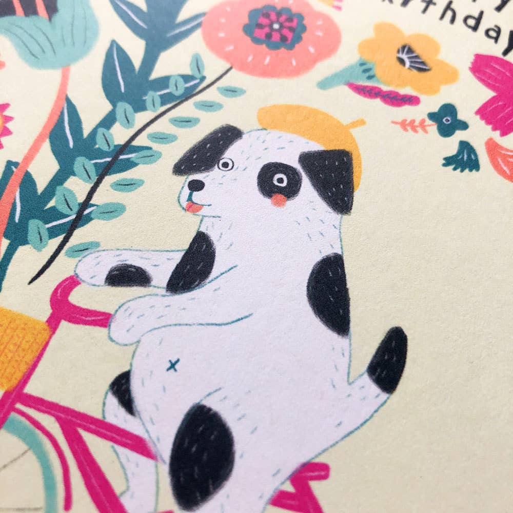 Illustration of a dog on a bicycle with colorful flowers and leaves in the background
