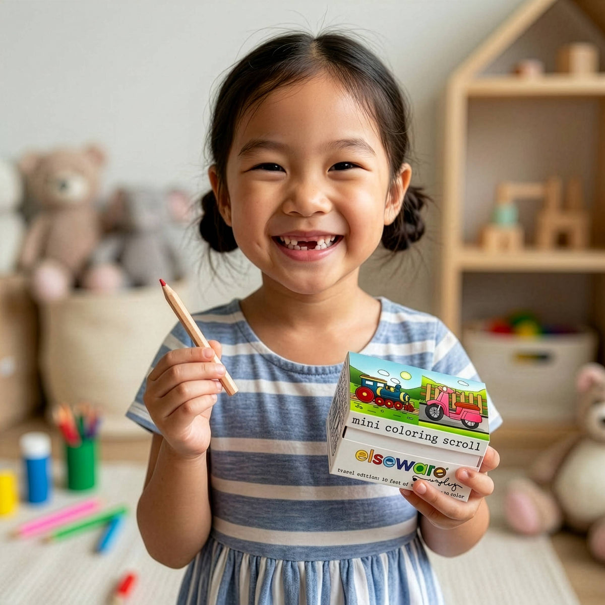 Child holding a coloring book and pencil in a playroom setting