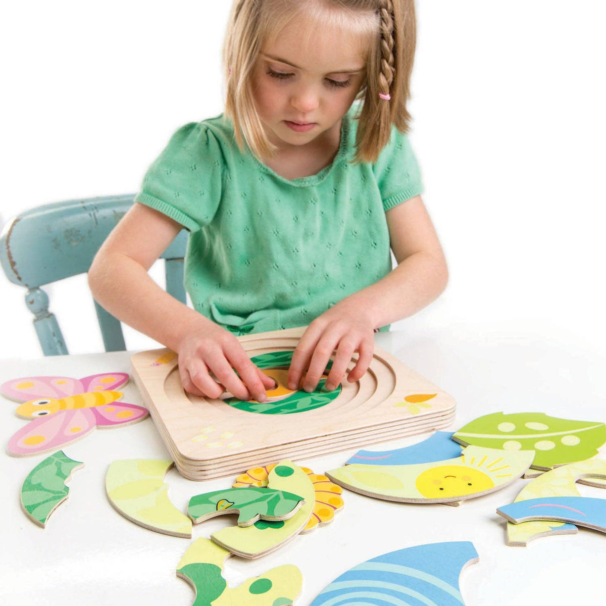 Child playing with a wooden puzzle on a white surface