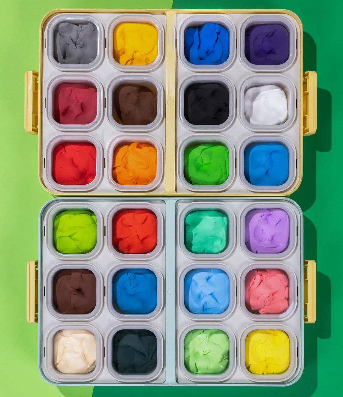 Set of colorful clay blocks in a metal tray on a green background