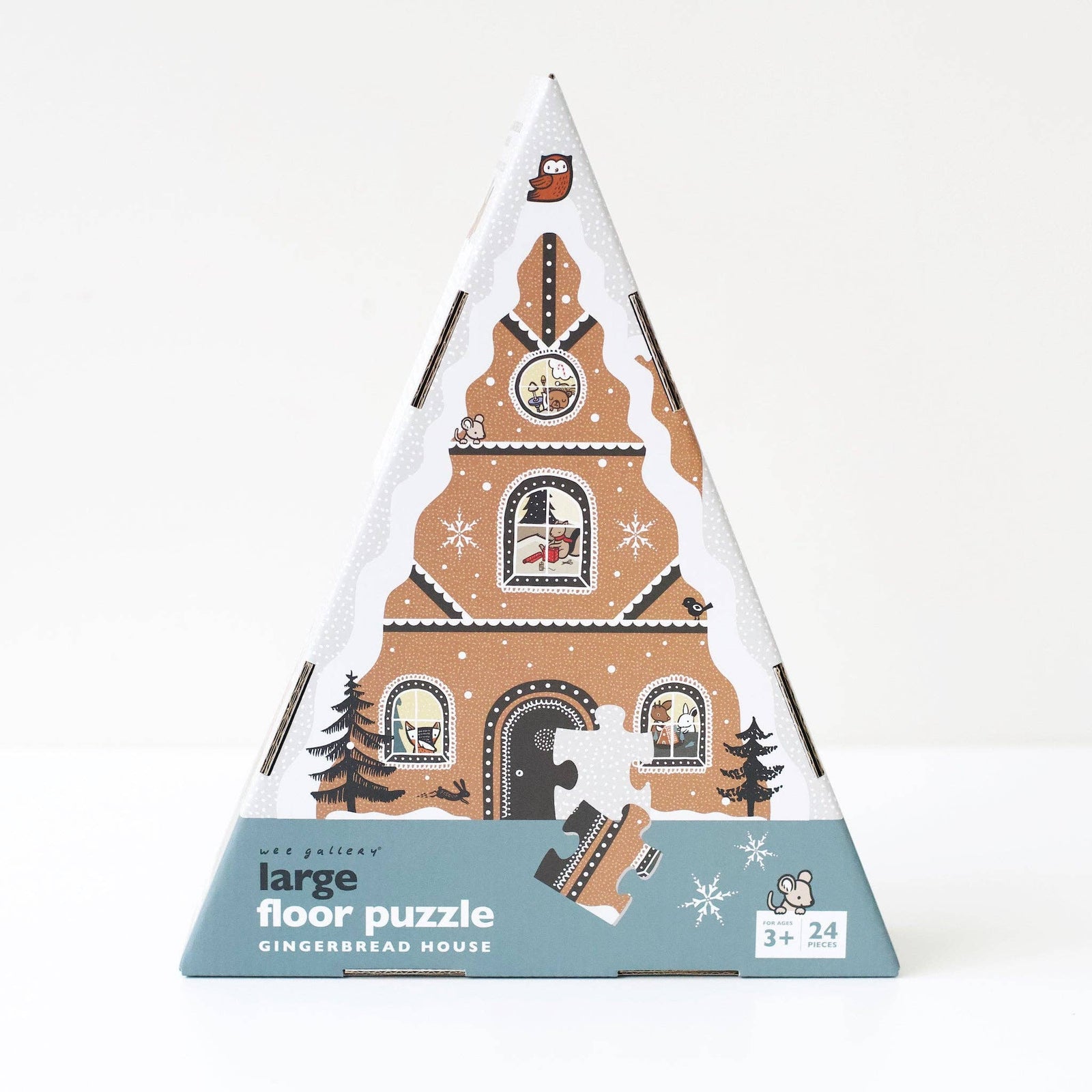 Triangular packaging of a large floor puzzle with gingerbread house design on a white background
