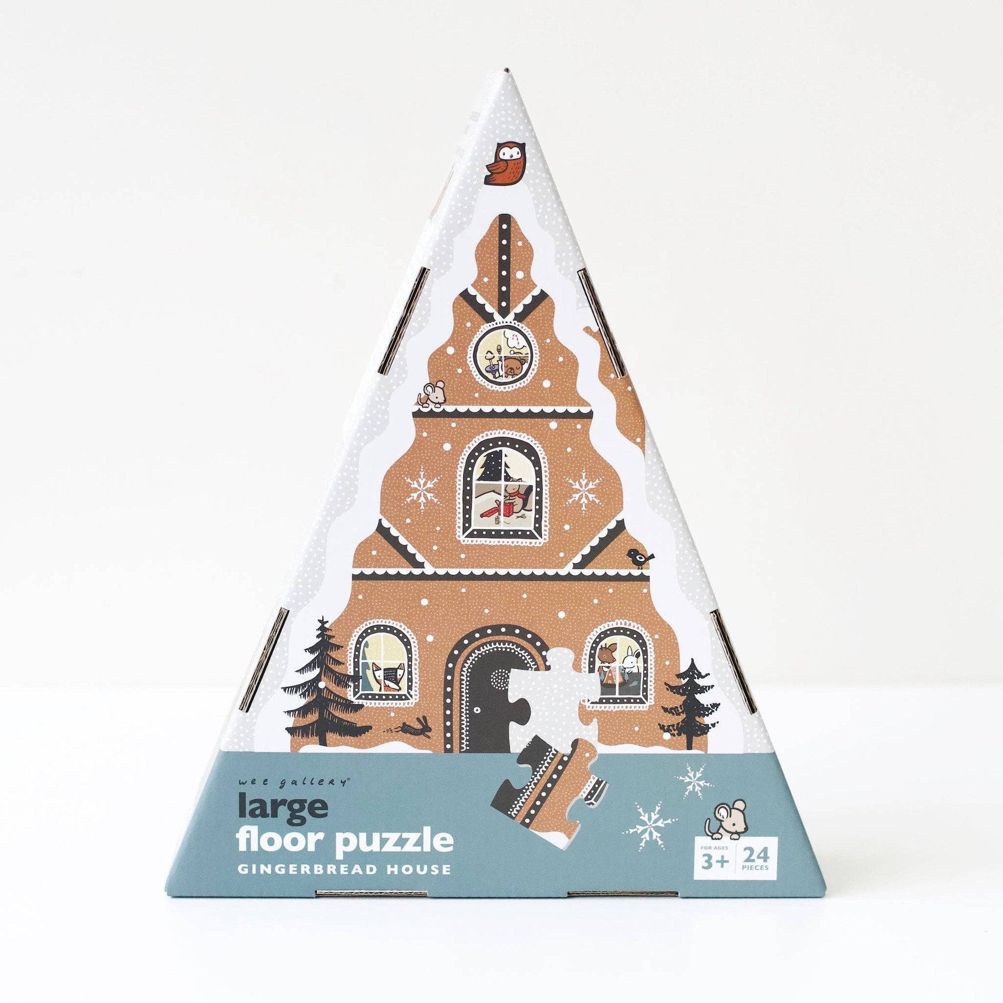 Triangular packaging of a large floor puzzle with gingerbread house design on a white background